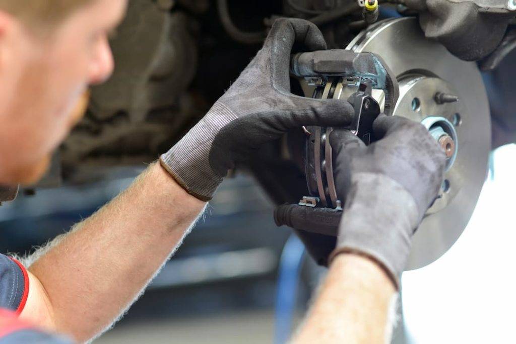 mechanic preforming brake inspections and checking brake pads